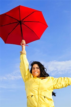 Portrait of beautiful girl wearing yellow raincoat holding red umbrella on windy day Stock Photo - Budget Royalty-Free & Subscription, Code: 400-04121695