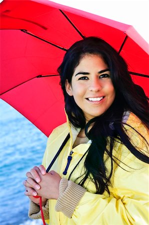 simsearch:614-02680509,k - Portrait of beautiful smiling brunette girl wearing yellow raincoat holding red umbrella Foto de stock - Royalty-Free Super Valor e Assinatura, Número: 400-04121693