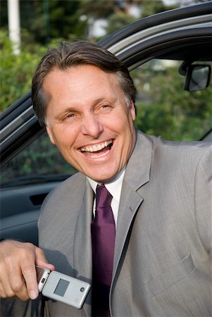 A happy laughing forties businessman is sitting in his car and laughing while holding his cellphone. Stock Photo - Budget Royalty-Free & Subscription, Code: 400-04122170