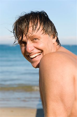 Handsome sexy forties man smiles at the camera as he enjoys a summer`s day on the beach. Foto de stock - Super Valor sin royalties y Suscripción, Código: 400-04122171