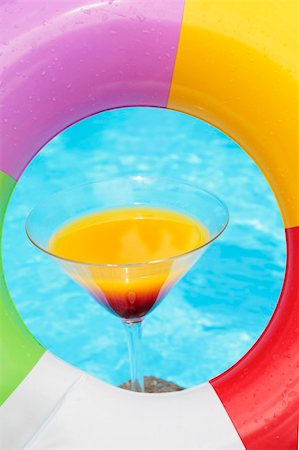 simsearch:400-08040653,k - Colorful cocktail in front of attractive blue pool water seen through a rubber ring Stock Photo - Budget Royalty-Free & Subscription, Code: 400-04122393