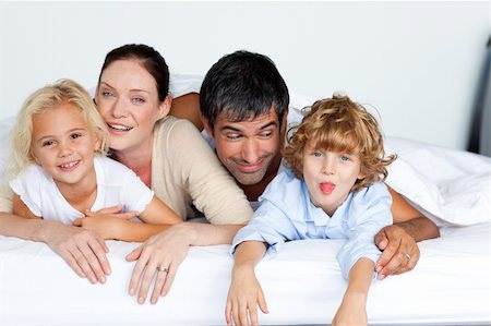 simsearch:400-04192370,k - Happy family lying together on bed Fotografie stock - Microstock e Abbonamento, Codice: 400-04123055