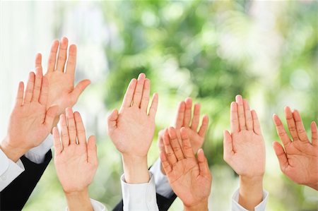 People raise their hands up to be picked up or to bid in an auction over green background Fotografie stock - Microstock e Abbonamento, Codice: 400-04138594