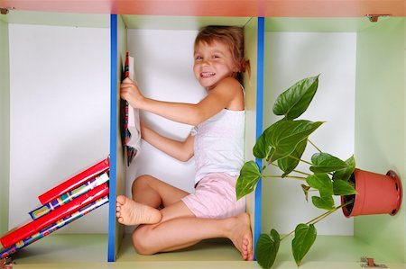 smiling little girl lying on a bookshelf and reading Stock Photo - Budget Royalty-Free & Subscription, Code: 400-04145378