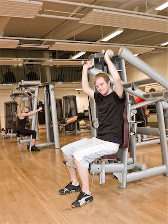 simsearch:400-04149259,k - Young man using an exercise machine at a health club with a girl and a boy in the background Stock Photo - Budget Royalty-Free & Subscription, Code: 400-04148002