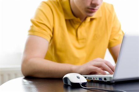 Young man in yellow shirt is sitting in front of his notebook (shallow DOF) Stock Photo - Budget Royalty-Free & Subscription, Code: 400-04148097