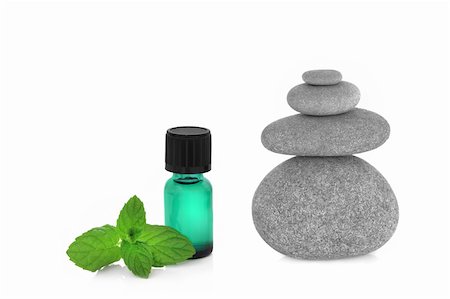 simsearch:400-04118662,k - Spa massage treament stones in perfect balance with peppermint herb leaf sprig and aromatherapy essential oil dropper bottle, over white background. Photographie de stock - Aubaine LD & Abonnement, Code: 400-04148945