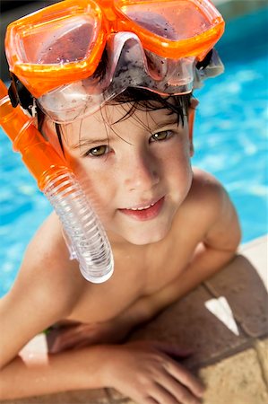 smile as mask for boy - A happy young boy relaxing on the side of a swimming pool wearing orange goggles and snorkel Stock Photo - Budget Royalty-Free & Subscription, Code: 400-04149662