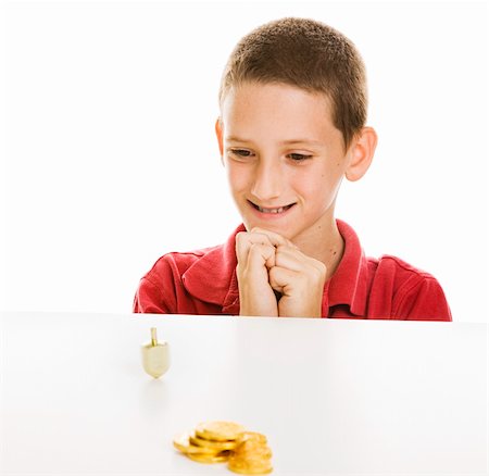 dreidel - Boy watching a Hanukkah dreidel spin, with chocolate gelt in the foreground.  Isolated on white. Photographie de stock - Aubaine LD & Abonnement, Code: 400-04149751