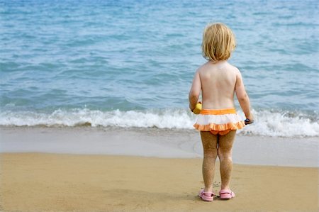 Blond little girl with sandy legs walking to turquoise beach Stock Photo - Budget Royalty-Free & Subscription, Code: 400-04140672