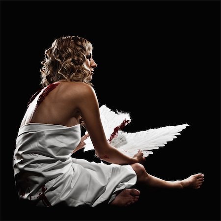 simsearch:649-07437240,k - A young, adult female model is sitting and draped in white fabric. She is in profile and looking away from the camera. She is holding wings that she has taken from her back as indicated by bloody back wounds. The shot is in a square format. Fotografie stock - Microstock e Abbonamento, Codice: 400-04141520