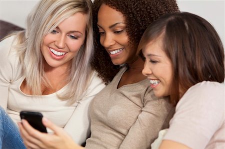 simsearch:6109-06003320,k - Three beautiful young women having fun looking at something funny on their smart cell phone and laughing Foto de stock - Royalty-Free Super Valor e Assinatura, Número: 400-04142557