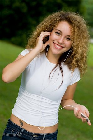 eastwestimaging (artist) - A young woman listening to music on a portable mp3 player in the park Fotografie stock - Microstock e Abbonamento, Codice: 400-04143585