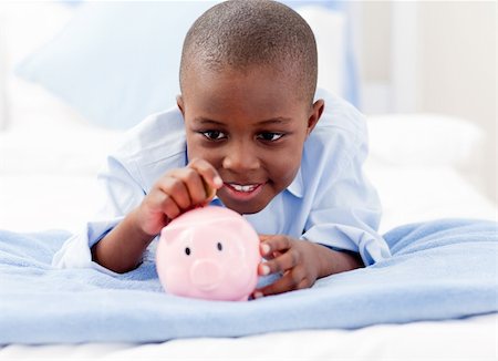 saving money black - Young Boy lying on his bed putting money into a piggy bank Stock Photo - Budget Royalty-Free & Subscription, Code: 400-04154775