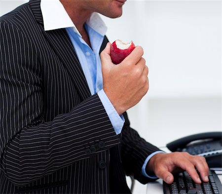 Close-up of a businessman eating a fruit at work Stock Photo - Budget Royalty-Free & Subscription, Code: 400-04157304