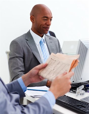 Smiling businessman working at a computer with his colleague reading a newspaper in the foreground Stock Photo - Budget Royalty-Free & Subscription, Code: 400-04157415