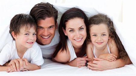 simsearch:400-05749479,k - Portrait of a smiling family lying on bed in parent's bedroom Foto de stock - Royalty-Free Super Valor e Assinatura, Número: 400-04157474