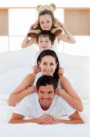 simsearch:400-05749479,k - Happy Parents and children playing on bed together Foto de stock - Royalty-Free Super Valor e Assinatura, Número: 400-04157482