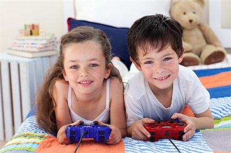 simsearch:400-04157521,k - Siblings playing video games together and lying on bed Stock Photo - Budget Royalty-Free & Subscription, Code: 400-04157524