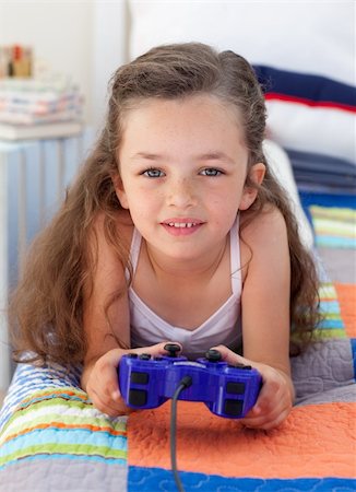 simsearch:400-04157519,k - Little girl playing video games and lying on bed Stock Photo - Budget Royalty-Free & Subscription, Code: 400-04157527