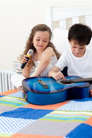 Brother and sister having fun with a guitar in the bedroom Stock Photo - Budget Royalty-Free & Subscription, Code: 400-04157520