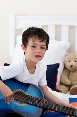 Portrait of a little boy playing guitar on bed Stock Photo - Budget Royalty-Free & Subscription, Code: 400-04157523