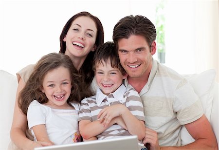 Smiling young family using a laptop in the living-room Stock Photo - Budget Royalty-Free & Subscription, Code: 400-04157548