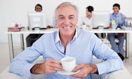 simsearch:400-04204942,k - Senior businessman drinking a coffee with his team in the background Stock Photo - Budget Royalty-Free & Subscription, Code: 400-04159705