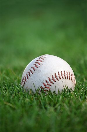 An old well-used baseball sitting in the grass of the outfield. Plenty of space for text. Selective focus on red stitches. Stock Photo - Budget Royalty-Free & Subscription, Code: 400-04159958