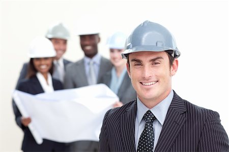 Attractive male architect with his team in the background smiling at the camera Stock Photo - Budget Royalty-Free & Subscription, Code: 400-04150380