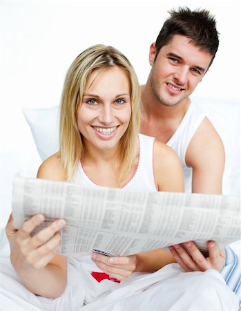 simsearch:400-04878558,k - Young couple with a newspaper in bed smiling at the camera Stock Photo - Budget Royalty-Free & Subscription, Code: 400-04150411