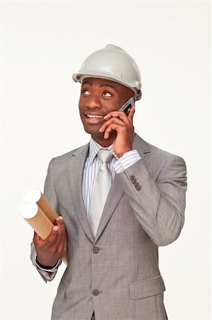 Smiling Afro-American architect speaking on mobile phone and holding plans against white background Stock Photo - Budget Royalty-Free & Subscription, Code: 400-04150487