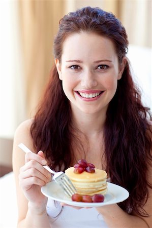 Smiling woman eating a sweet dessert in bedroom Stock Photo - Budget Royalty-Free & Subscription, Code: 400-04150681