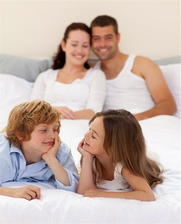 simsearch:400-04192370,k - Little brother and sister looking at each other in bed with her parents Stock Photo - Budget Royalty-Free & Subscription, Code: 400-04151146