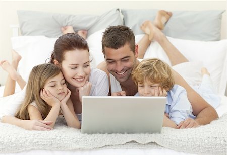 Family lying in bed using a laptop Stock Photo - Budget Royalty-Free & Subscription, Code: 400-04151158