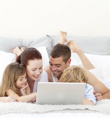 Parents and children lying in bed playing with a laptop Stock Photo - Budget Royalty-Free & Subscription, Code: 400-04151162