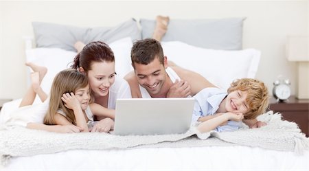 Family lying in bed using a laptop Stock Photo - Budget Royalty-Free & Subscription, Code: 400-04151163
