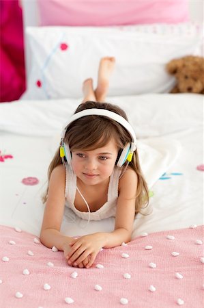 simsearch:400-05717354,k - Smiling little girl lying in bed listening to the music Stock Photo - Budget Royalty-Free & Subscription, Code: 400-04151237