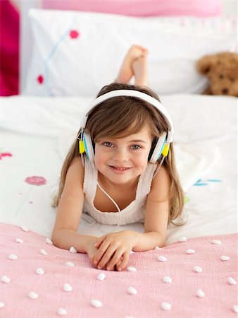 simsearch:400-05717354,k - Smiling little girl lying in bed listening to the music Stock Photo - Budget Royalty-Free & Subscription, Code: 400-04151238