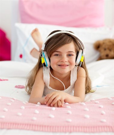 simsearch:400-05717354,k - Smiling little girl lying in bed listening to the music Stock Photo - Budget Royalty-Free & Subscription, Code: 400-04151239