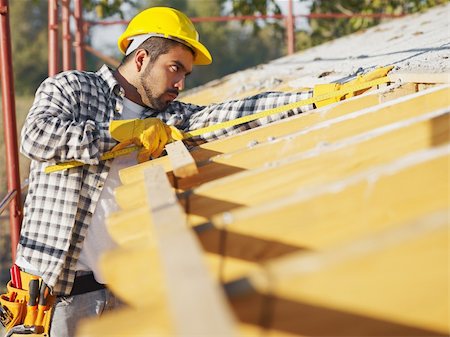 latin american construction worker on house roof with measuring tape. Copy space Stock Photo - Budget Royalty-Free & Subscription, Code: 400-04151372