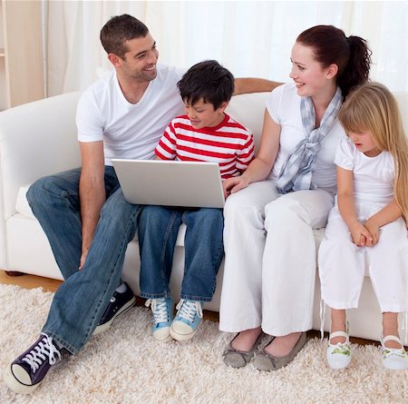 simsearch:400-04575374,k - Smiling family in living-room using a laptop sitting on sofa Stock Photo - Budget Royalty-Free & Subscription, Code: 400-04151983