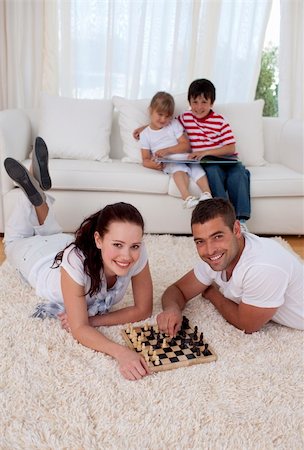 simsearch:400-04467628,k - Couple playing chess on floor in living-room with their children on sofa Photographie de stock - Aubaine LD & Abonnement, Code: 400-04152010