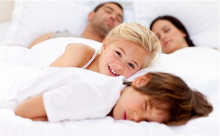 Smiling daughter relaxing with her brother and parents sleeping in bed Stock Photo - Budget Royalty-Free & Subscription, Code: 400-04152122