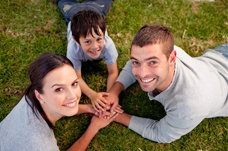 Happy parents and kid lying on garden with hands together Stock Photo - Budget Royalty-Free & Subscription, Code: 400-04152153