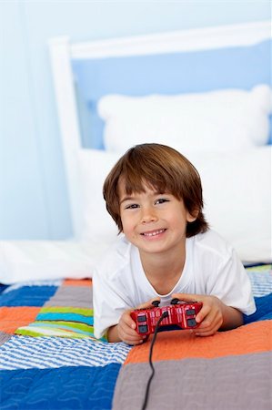 simsearch:400-04199147,k - Smiling little boy playing videogames in his bedroom Photographie de stock - Aubaine LD & Abonnement, Code: 400-04152175