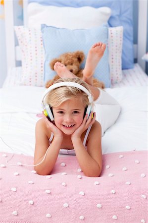 simsearch:400-05717354,k - Smiling little girl lying in bed with a headphones on listening to the music Stock Photo - Budget Royalty-Free & Subscription, Code: 400-04152170