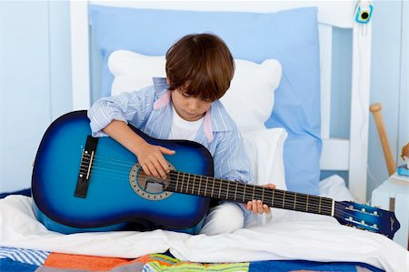 simsearch:400-05745955,k - Happy little boy playing guitar in bed Foto de stock - Royalty-Free Super Valor e Assinatura, Número: 400-04152180