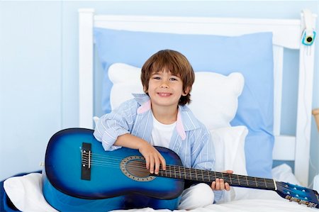 Happy little boy playing guitar sitting in bed Stock Photo - Budget Royalty-Free & Subscription, Code: 400-04152181