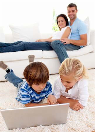 simsearch:400-04575374,k - Children using a laptop on floor and parents lying on sofa Stock Photo - Budget Royalty-Free & Subscription, Code: 400-04152223